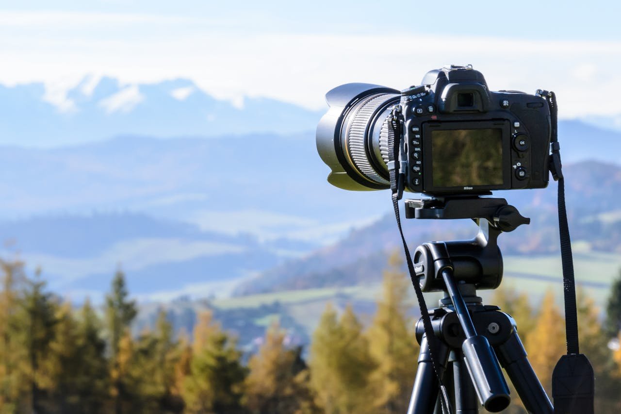 home-img DSLR camera on tripod capturing a stunning mountain view on a clear day.