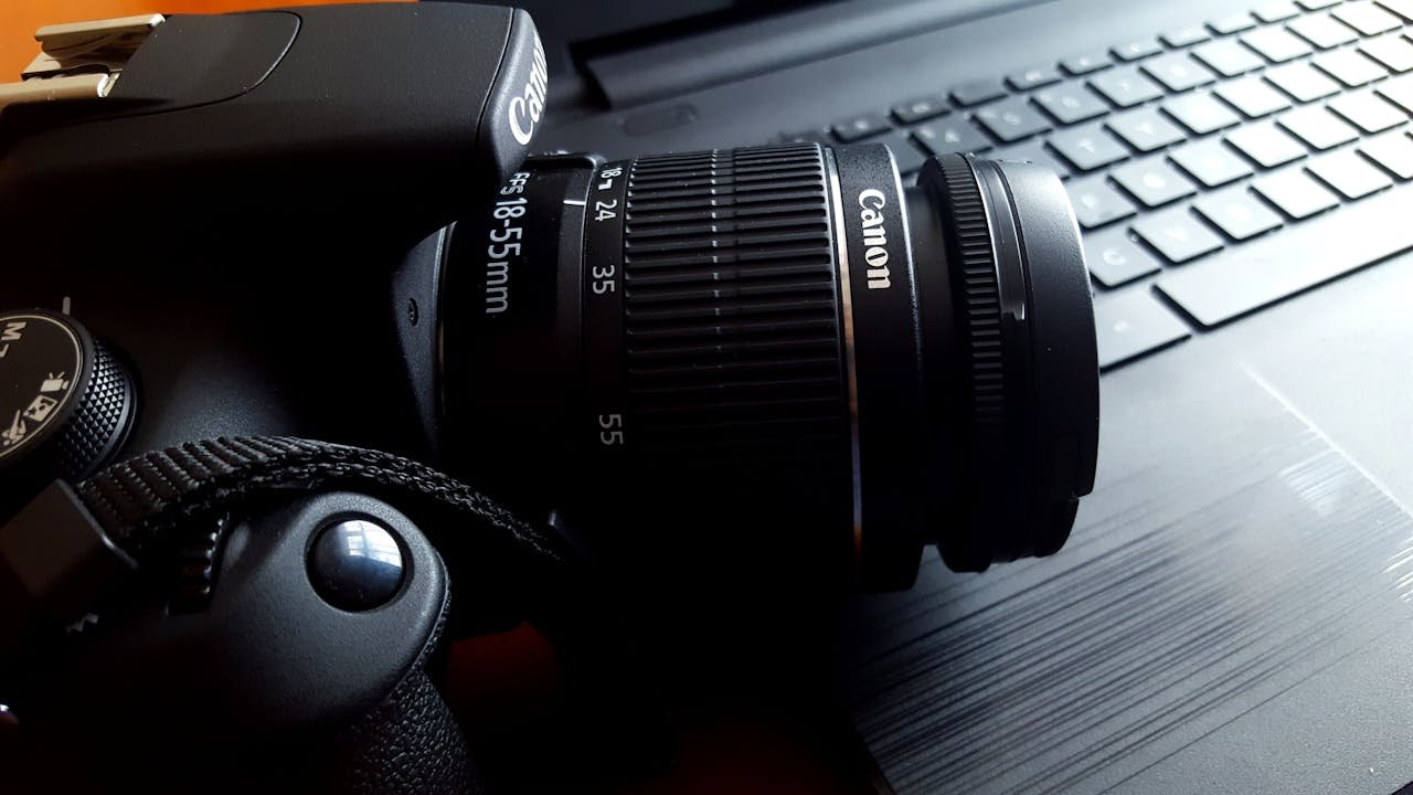 services-01 Close-up of a black DSLR camera with lens on a laptop keyboard.