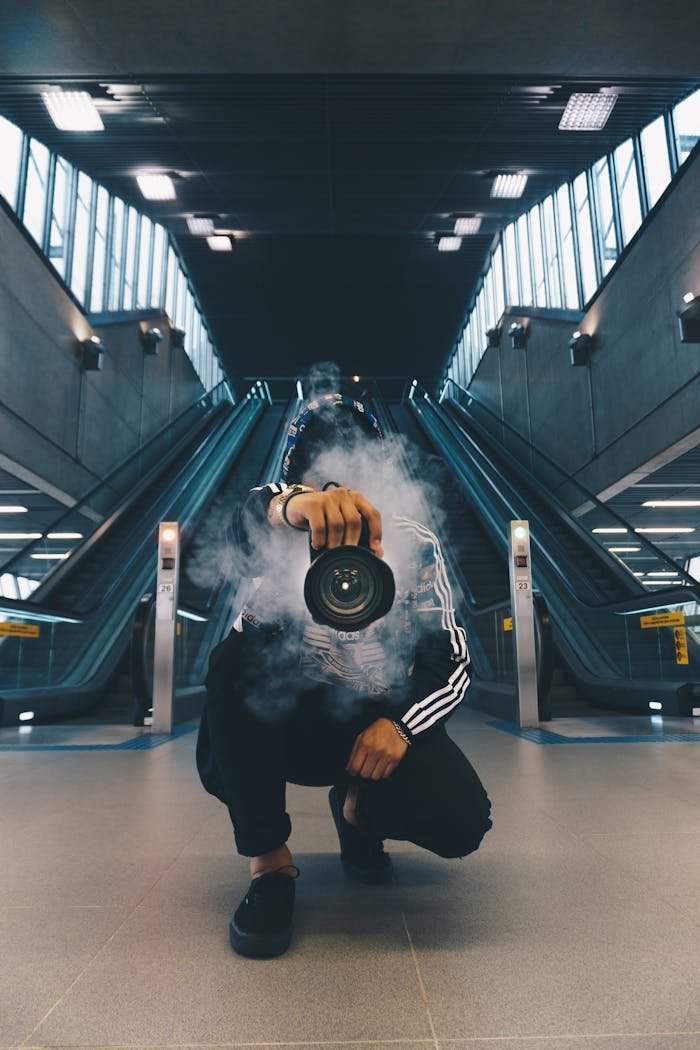 gallery-03 Person holding a camera in a smoke-filled urban setting with escalators.