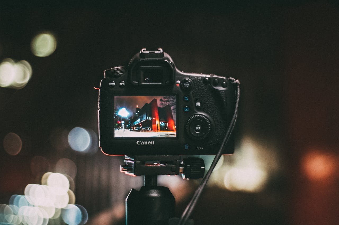 services-img Close-up of a camera capturing a vibrant urban scene at night with a blurred bokeh background.